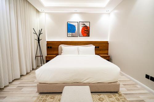 a bedroom with a large white bed and two paintings at Spacious room and hall in Sulaymaniyah 309 in Riyadh