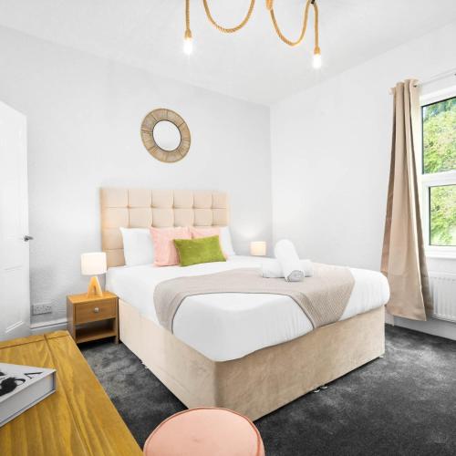 a white bedroom with a large bed with pink and green pillows at Stylish Three Bed House - Parking - Garden - Netflix 17ML in Birmingham