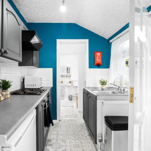 a kitchen with blue walls and a counter top at Stylish Three Bed House - Parking - Garden - Netflix 17ML in Birmingham