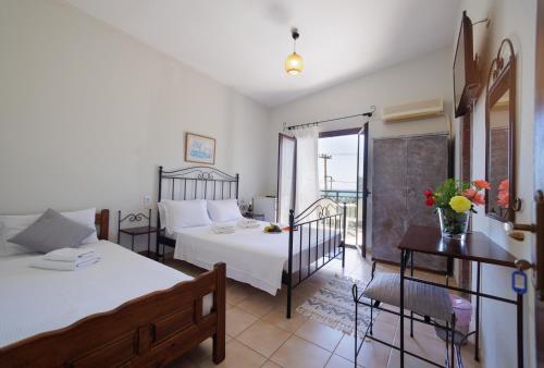 a bedroom with two beds and a table and a balcony at LITHOS by the sea in Neo Itilo