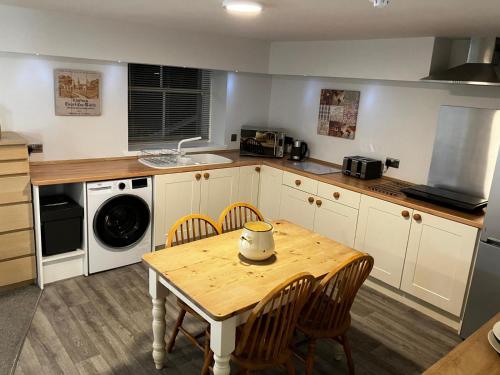 een keuken met een tafel, stoelen en een spoelbak bij The Bunker Self Catering in Nairn