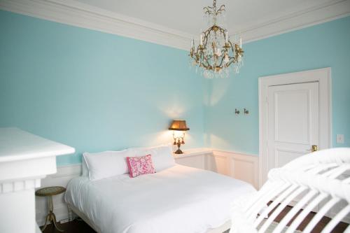 a bedroom with a white bed and a chandelier at Bosch House Rosé - Zee Suite in Savannah