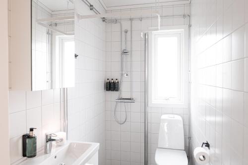 um banheiro branco com chuveiro e pia em Skerike Golfhus em Västerås