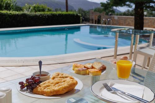 a table with plates of food and drinks and a pool at LITHOS by the sea in Neon Oitilon