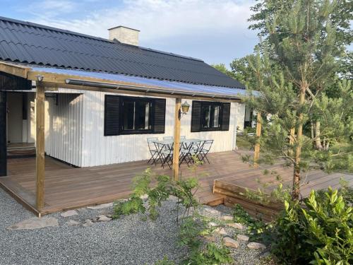 ein Haus mit einer Holzterrasse mit einem Tisch in der Unterkunft Holiday Home Alica - 200m from the sea by Interhome in Neksø