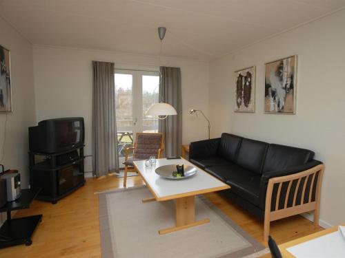 a living room with a black couch and a table at Apartment Runhild - 100m from the sea by Interhome in Hals