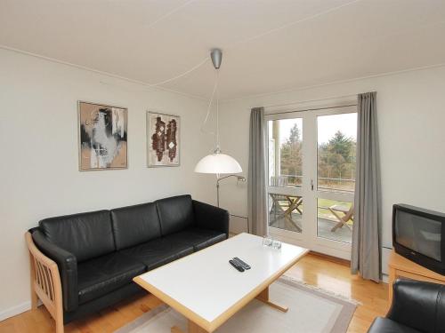 a living room with a black couch and a table at Apartment Enni - 100m from the sea by Interhome in Hals