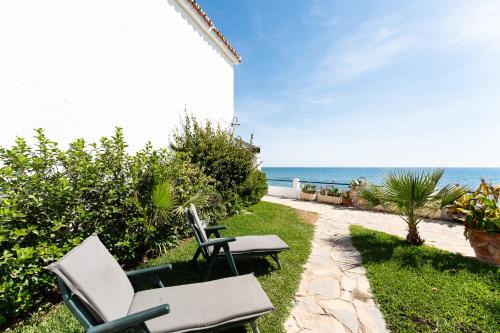 a patio with chairs and the ocean in the background at Newly Renovated 2 Bedroom Beachfront House in Sitio de Calahonda