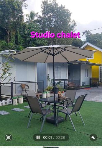 a patio with a table and chairs and an umbrella at Cheqma Tiny Chalet in Kota Bharu