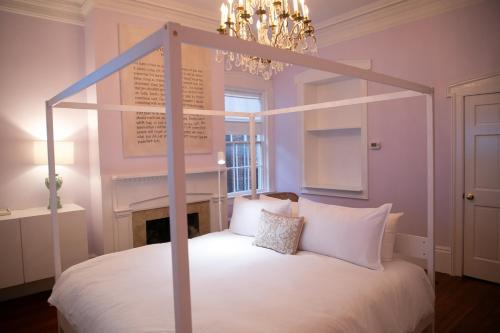 a bedroom with a canopy bed and a chandelier at Bosch House Rosé - Lila Suite in Savannah
