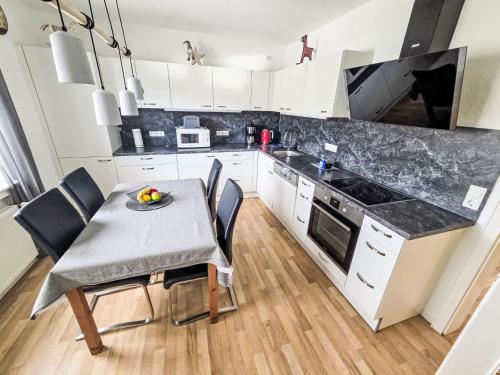 eine Küche mit einem Tisch und Stühlen sowie eine Küche mit weißen Schränken in der Unterkunft Apartment Lindenstraße-1 by Interhome in Wöbbel