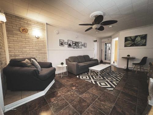 a living room with a couch and a ceiling fan at Auberge Le Chic in Maniwaki