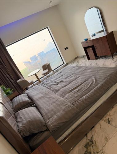 Una cama grande en una habitación con una ventana grande. en شاليه داله العماريه 3 بالكامل لك وأجواء ممتعه, en Al ‘Ammārīyah