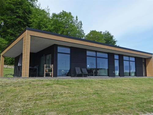 a building with windows and chairs in a field at Holiday Home Hildegunda - 600m from the sea by Interhome in Sjølund