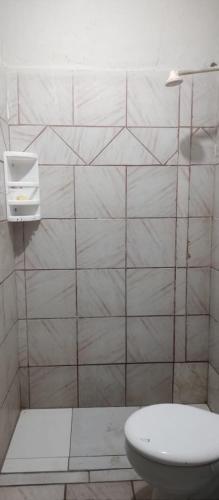 a bathroom with a toilet and a tiled wall at 02 - Sinta-se em casa in Paragominas