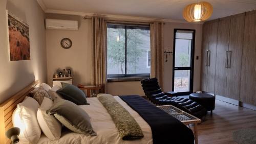 een slaapkamer met een groot bed en een stoel bij Stay at 64 Omeya in Windhoek