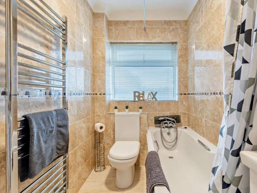 a bathroom with a toilet and a tub and a sink at 2 Bed in Bacton 75392 in Bacton
