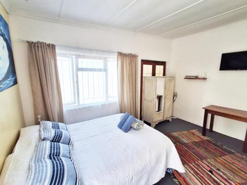 a small bedroom with a bed and a window at Bokkomblommetjie in Lambertʼs Bay