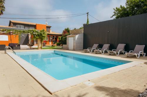 a swimming pool with lounge chairs next to a house at Verde Verdilhão Villa