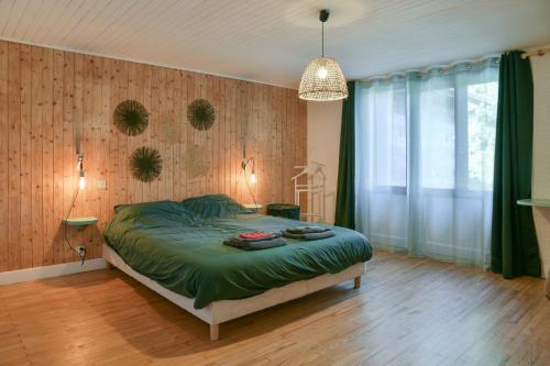 een slaapkamer met een bed met een groen dekbed bij Nature et Calme Entre Deux Lacs in La Biolle