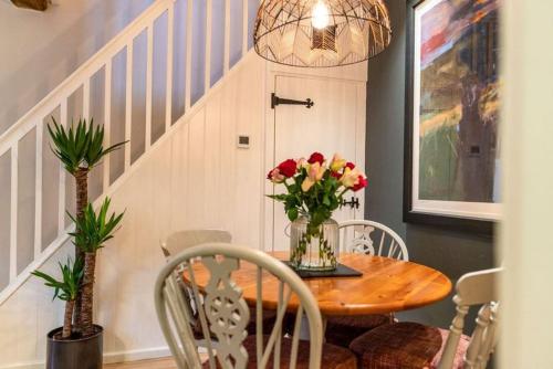 a dining room with a table with a vase of flowers at The Clock House in Chichester