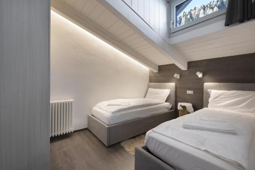 a attic room with two beds and a window at Mansarda Angel's Home in Ponte di Legno
