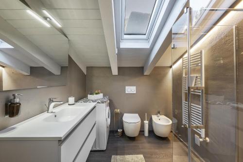 a bathroom with a sink and a toilet and a skylight at Mansarda Angel's Home in Ponte di Legno