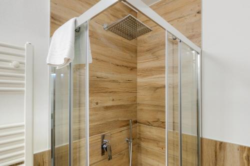 a shower in a bathroom with wooden walls at Hostdomus - Valle Studio in Grange Sises