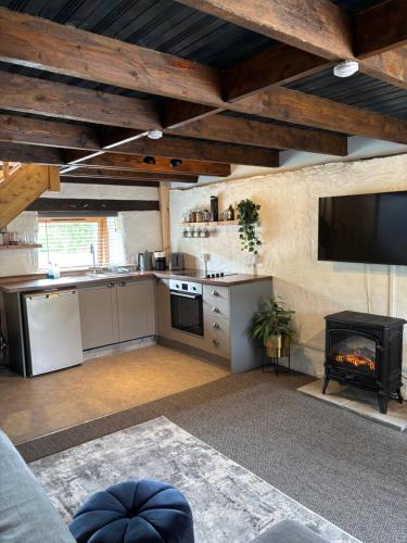 een woonkamer met een keuken en een open haard bij Old Stone Byre in Totaig