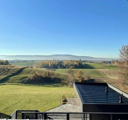 a house with a view of a green field at Stodoła Na Kresach - widokowy domek drewniany, całoroczny JACUZZI & SAUNA in Bodzentyn