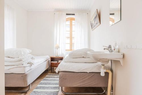 a white bedroom with a sink and a bed at Franshammars vandrarhem in Hassela