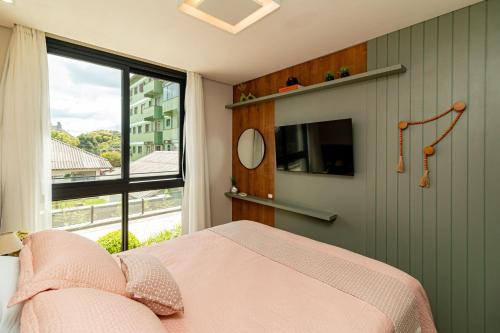 ein Schlafzimmer mit einem rosa Bett und einem Fenster in der Unterkunft Apto Moderno e Confortável no Coração de Canela in Canela
