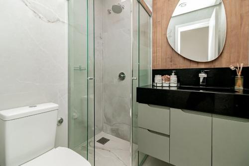 ein Bad mit einer Dusche, einem WC und einem Spiegel in der Unterkunft Apto Moderno e Confortável no Coração de Canela in Canela