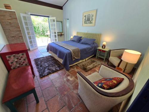 a bedroom with a bed and a couch and a chair at Pousada Quintal das Hortênsias in Salesópolis