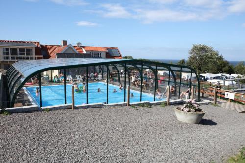 a swimming pool with people in a building at Sandkaas Family Camping & Cottages in Allinge