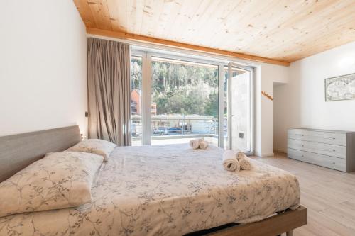 a bedroom with a large bed and a large window at Appartamento Jubilant in Comano