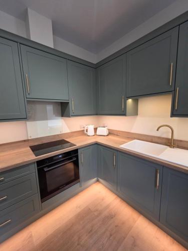 a kitchen with blue cabinets and a sink at Luxury studio flat, Skipton in Skipton