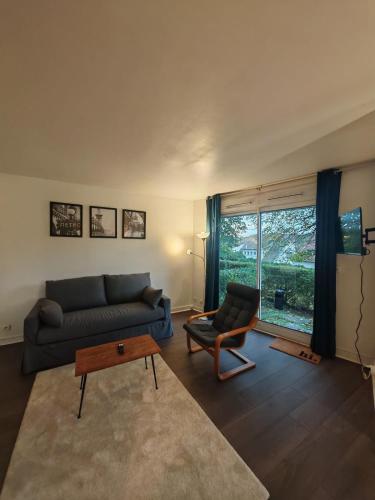 a living room with a couch and a chair at Charmant studio meublé avec jardinet - 25 m2 - Orsay - Le Guichet in Orsay