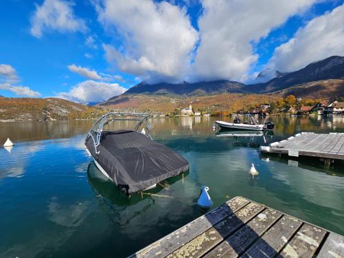 a boat is docked at a dock on a lake at Studio Vue sur le Lac d'Annecy Plage et Parking Privés in Duingt