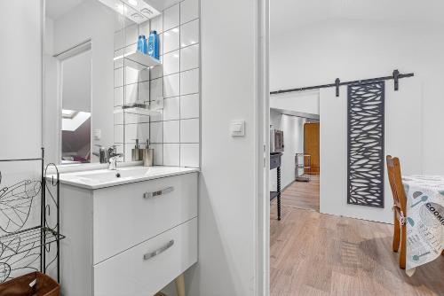 a white bathroom with a sink and a mirror at Gîte Uncinatum - La Grange Du Logis in Villevieille