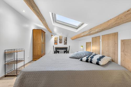 a bedroom with a large bed with a skylight at Gîte Uncinatum - La Grange Du Logis in Villevieille