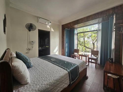 een slaapkamer met een bed, een raam en een tafel bij The Green House Homestay in Ninh Binh