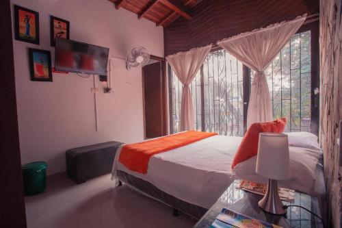 a bedroom with a bed and a tv and a window at Hotel Palma De Sevilla Medellin in Medellín