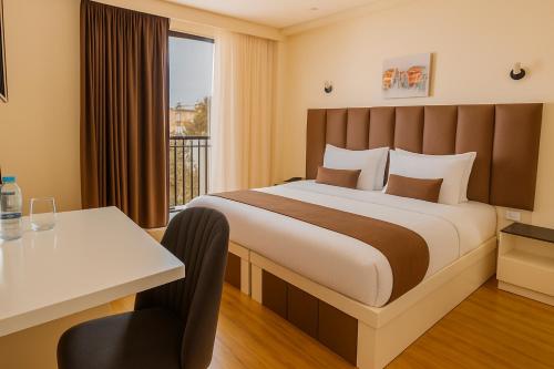 a bedroom with a bed and a desk and a window at Hotel Residence Plaza in Tbilisi City