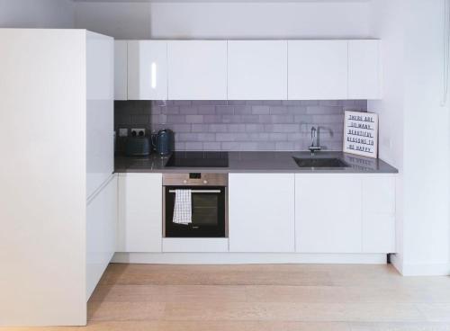 a kitchen with white cabinets and a sink at 1 Bedroom apartment near Canning Town in London