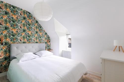 a bedroom with a white bed with a floral headboard at Gîte Kereliott in Lézardrieux