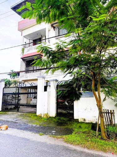 a white building with a black gate and a tree at Backpackers Bunkhouse Siliguri 8Bed WHY WAIT in Siliguri