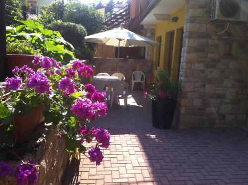 a patio with purple flowers and an umbrella at Apartment Sinčić in Novigrad Istria