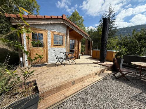 a cabin with a wooden deck with a table and chairs at Chalet d hiver in Millau
