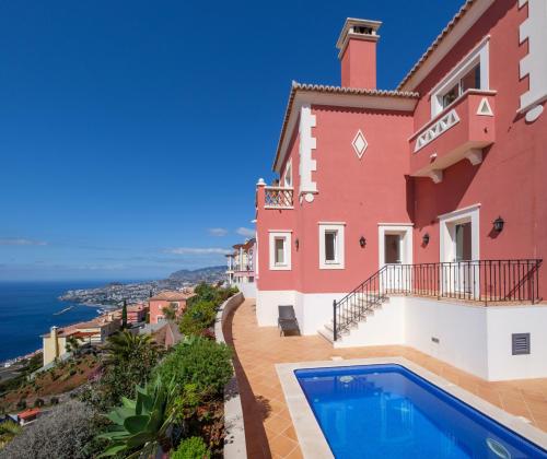 a villa with a swimming pool and a view of the ocean at Palheiro Village Resort in Funchal